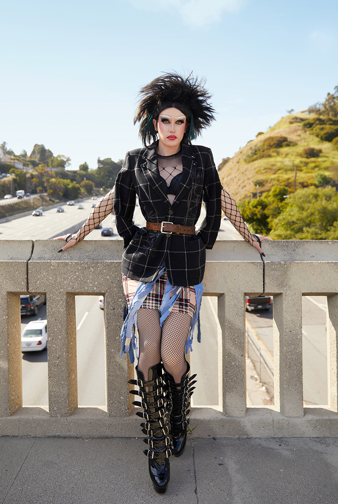 Jesse Clark in punk inspired drag leaning against a hand rail on a bridge over a freeway.